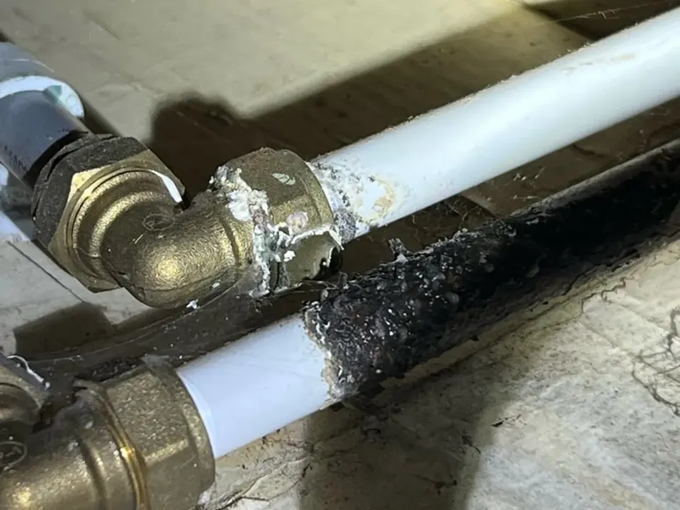 Corroded stop valve fitting with a failed joint beneath hallway floorboards