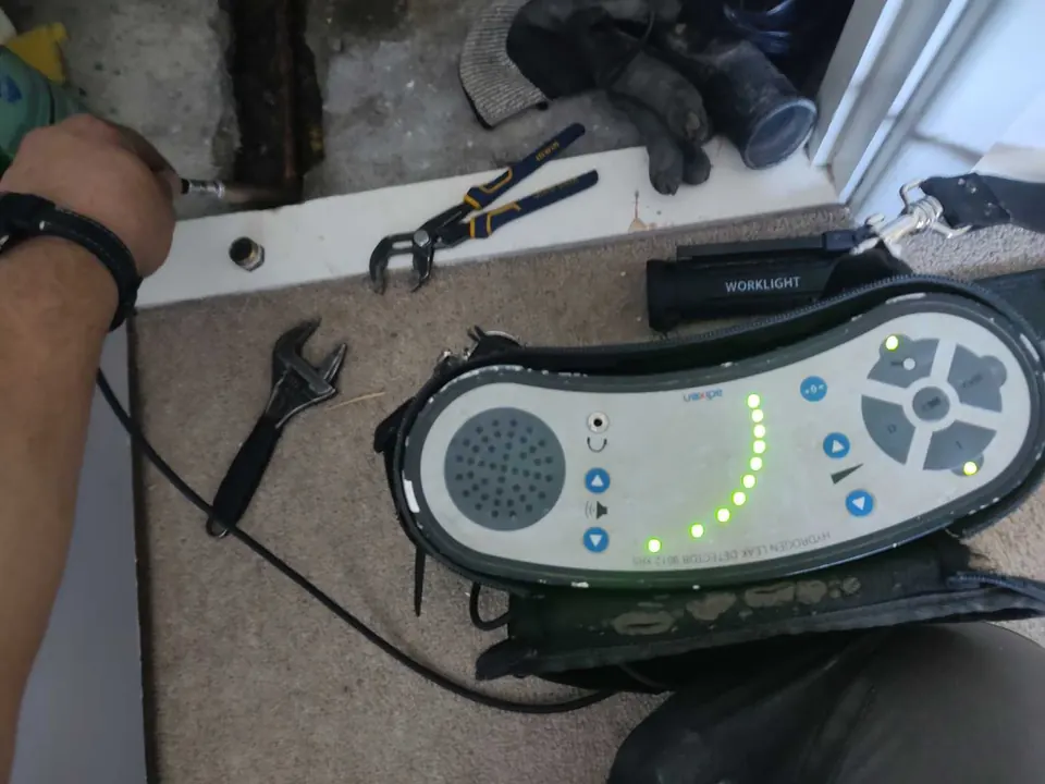Hydrogen tracer gas detector on the carpet beside the opened floor